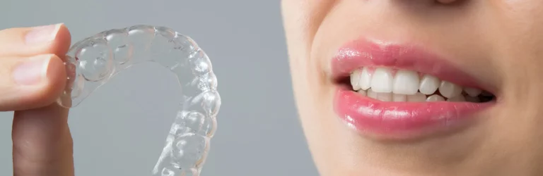 Person holding a clear dental aligner or retainer near their mouth, illustrating the use of modern orthodontic devices for dental care.
