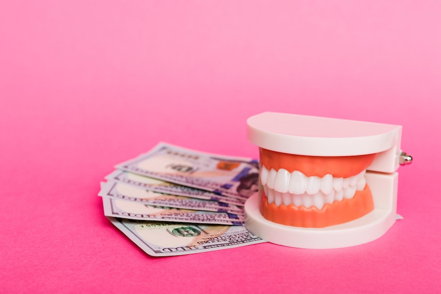 Model teeth with a stack of hundred-dollar bills, representing wisdom tooth removal costs.
